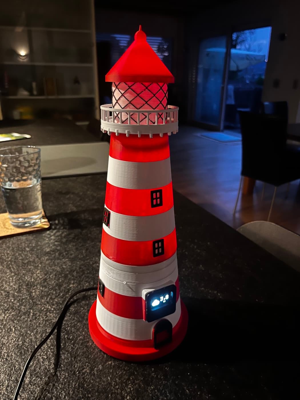 Der fertige Leuchtturm leuchtet im Dunkeln, auf dem kleinen Display sind die Wetterdaten zu sehen.